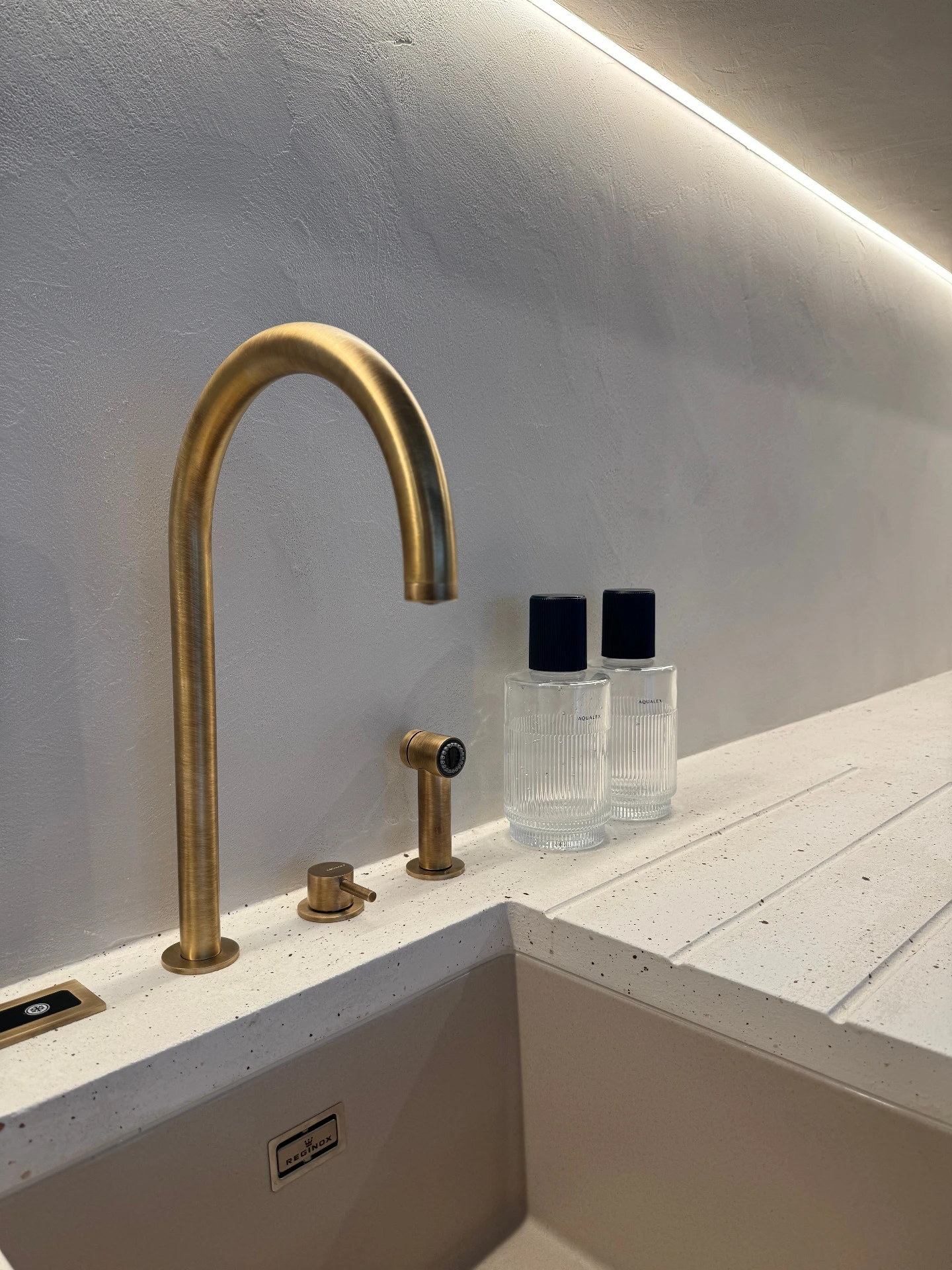 minimalistisch interieur met gouden kraan en wit komposiet aanrecht door interieurarchitect Frédéric Lammertyn